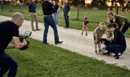 A man with a video camera capturing a farm family