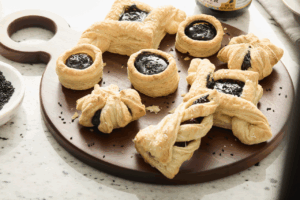 Pastries with black sesame filling sit on top of a circular wooden cutting board.