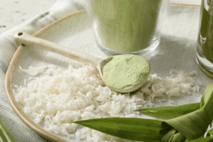 A large spoon holding green coconut pandan powder.