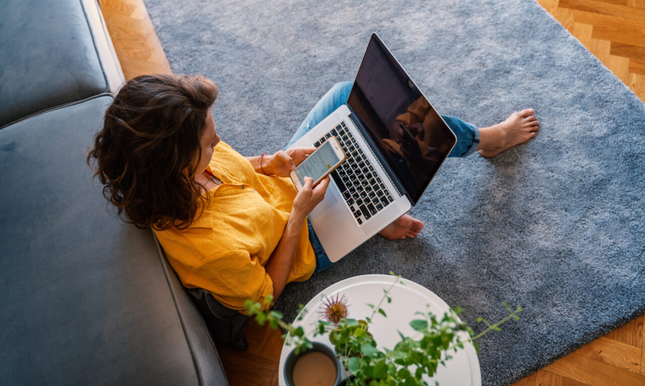 woman on her phone with computer on her lap