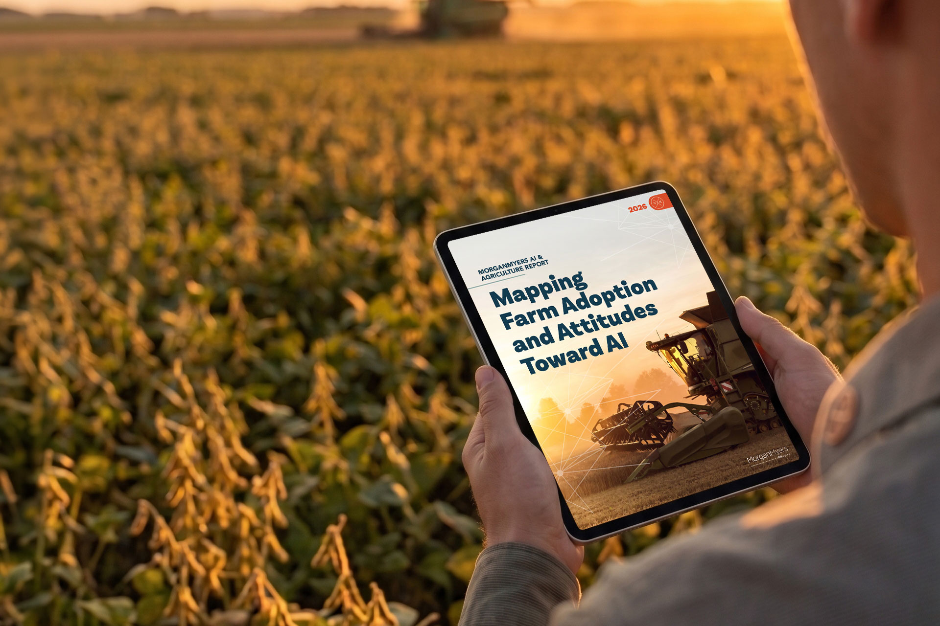 Photo of a farmer holding an iPad in a field showing the Mapping Farm Adoption and Attitudes Toward AI report from MorganMyers